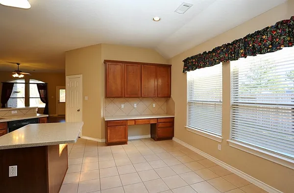 an empty room with chandelier fan and windows