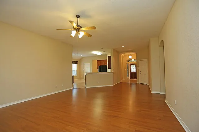 a view of an empty room with window and wooden floor