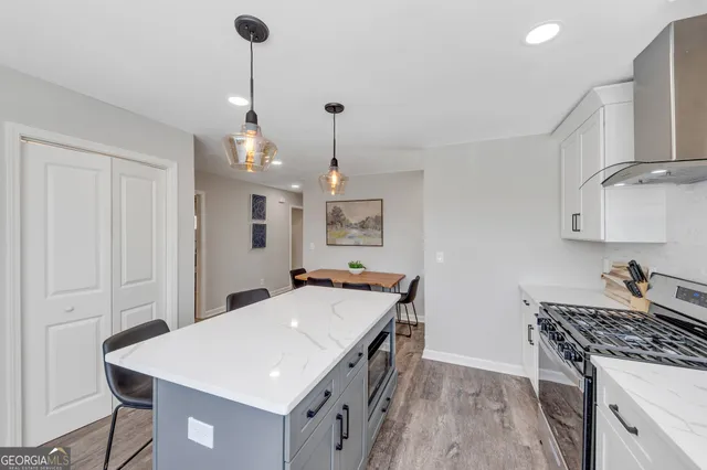 a kitchen with a stove a sink a refrigerator and chairs