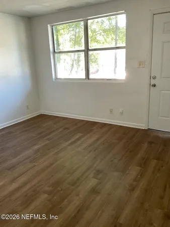 an empty room with wooden floor and windows