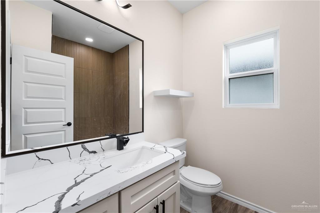 18054 Spruce Street Combes, TX 78552 - Photo 15 of 25 Modern bathroom featuring a vanity with a white countertop and dark veining, an integrated sink, and a matte black faucet