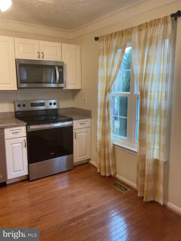 a kitchen with a refrigerator stainless steel appliances wooden floor and cabinets