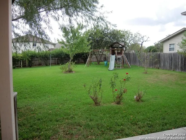 a backyard of a house with plants and wooden fence
