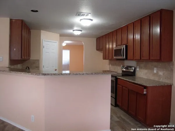 a kitchen with stainless steel appliances granite countertop wooden cabinets a refrigerator and a sink