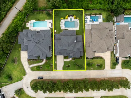 an aerial view of residential houses with outdoor space and trees