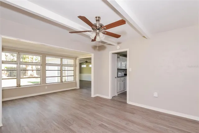 an empty room with wooden floor ceiling fan and windows