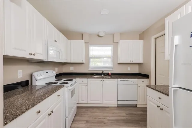 a kitchen with granite countertop white cabinets and white appliances