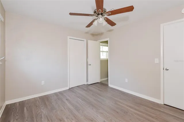 an empty room with wooden floor fan and windows