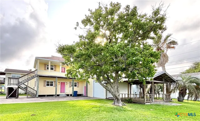 a view of a house with a big yard plants and large trees