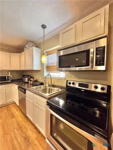 a kitchen with stainless steel appliances a stove a microwave and sink