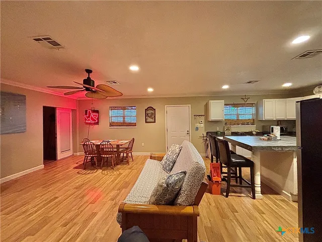 a dining hall with stainless steel appliances granite countertop a couch and a dining table with wooden floor