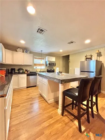 a kitchen with stainless steel appliances kitchen island granite countertop a table chairs sink and cabinets