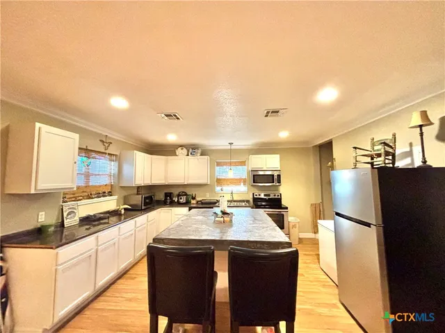 a kitchen with stainless steel appliances granite countertop a refrigerator a sink a stove a microwave and island