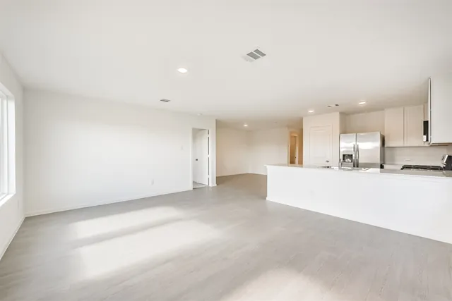 a kitchen with stainless steel appliances a refrigerator a sink a stove and white cabinets