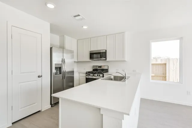 a kitchen with white cabinets and appliances