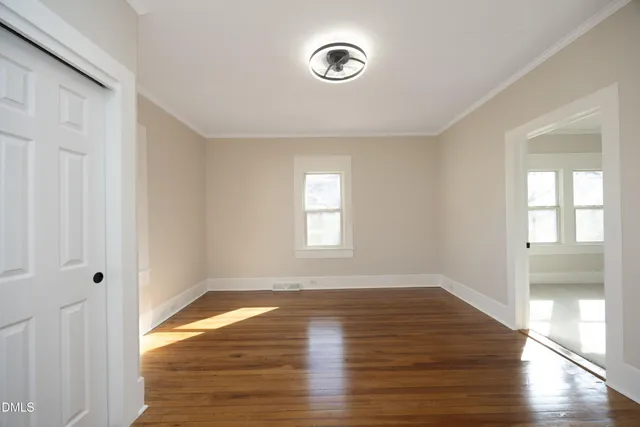 a view of empty room with wooden floor and fan