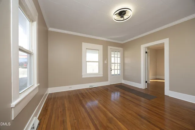 an empty room with wooden floor and windows