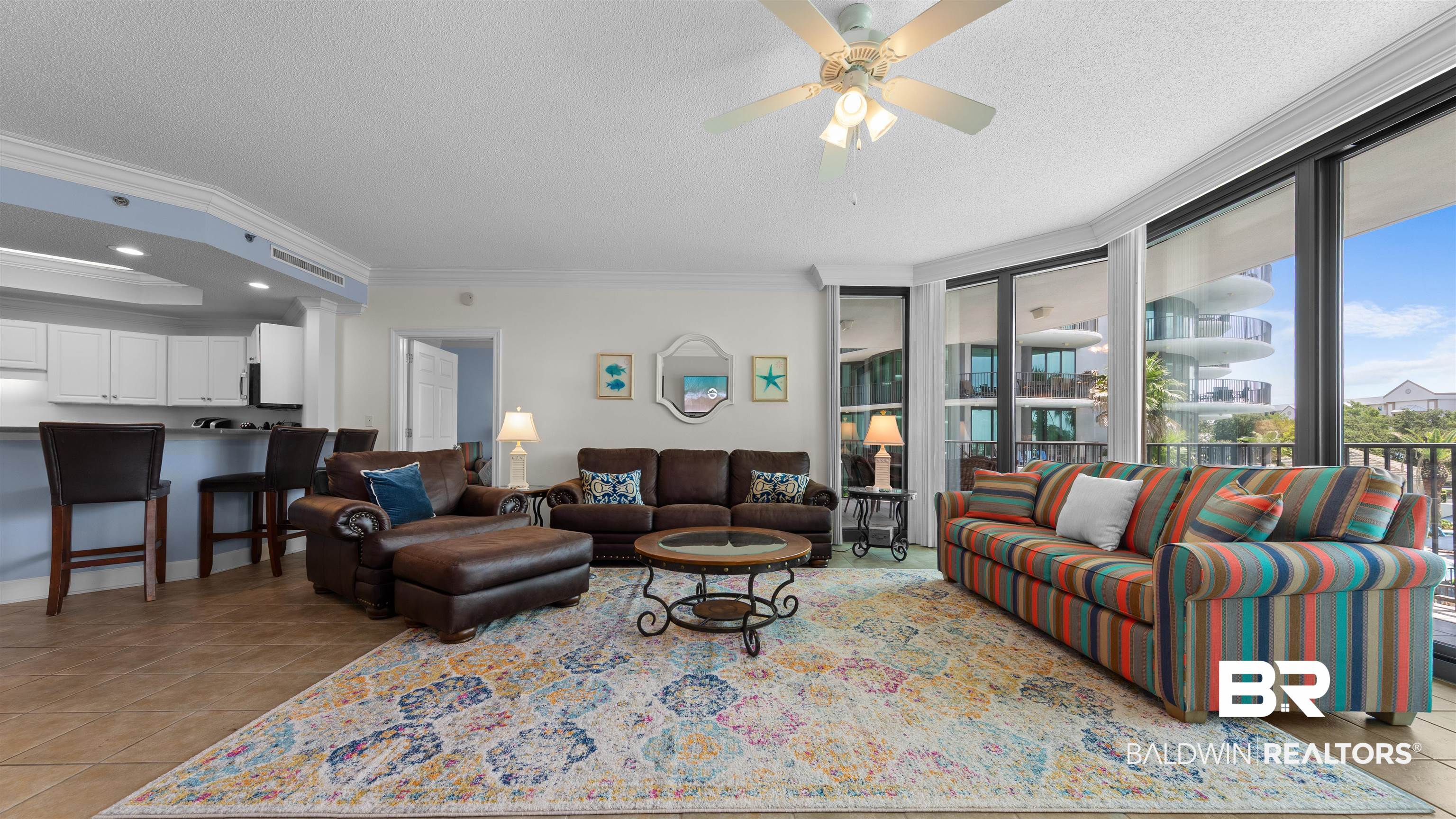 27582 Canal Road, Unit 2207 Orange Beach, AL 36561 - Photo 2 of 25 Living area with ornamental molding, light tile patterned flooring, a textured ceiling, a ceiling fan, and a raised ceiling