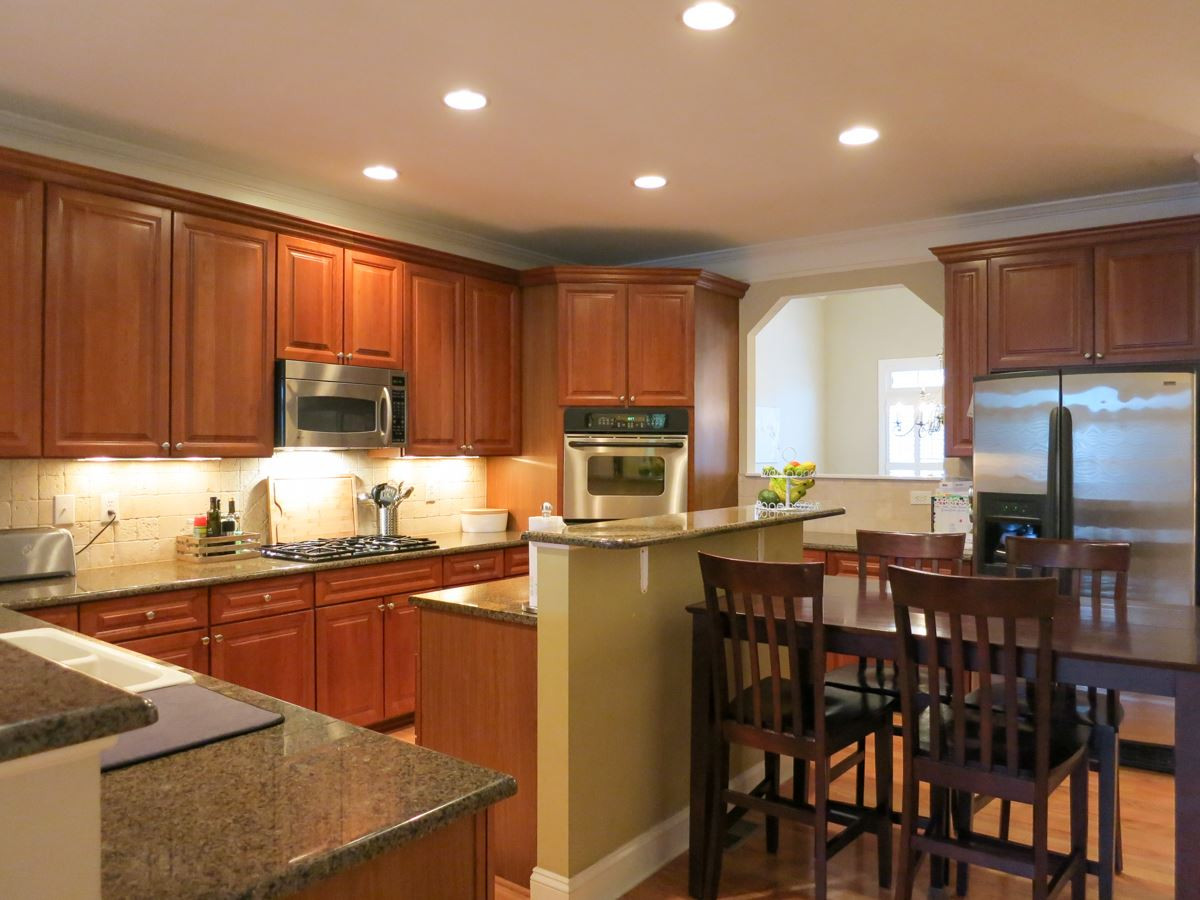 The Living Rm opens to the gourmet Kitchen w/lots of tall cherry cabinets, granite ctrs, SS appls (double wall ovens, gas cooktop, MW, DW), eat-at island, tile backsplash, recessed lights, hardwood flr, Bfast area & passthru to Dining Rm. Kitchen