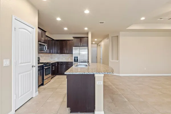 a large kitchen with stainless steel appliances granite countertop a refrigerator a sink a stove a microwave and island