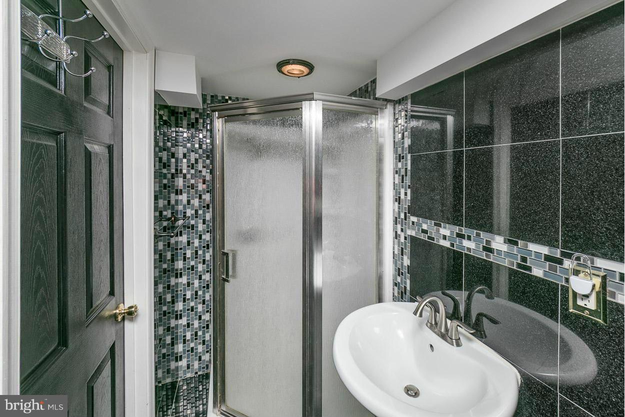 573 Brisbane Road Baltimore, MD 21229 - Photo 27 of 30 a bathroom with a shower sink and mirror