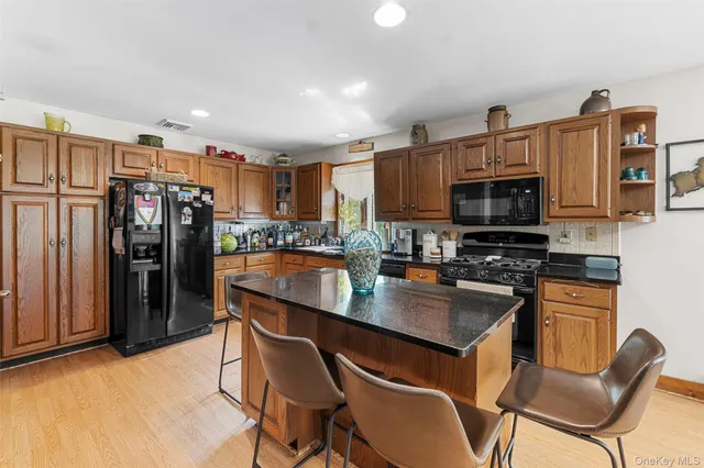 a kitchen with stainless steel appliances granite countertop wooden cabinets a dining table and chairs