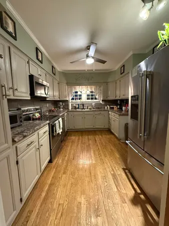 a large kitchen with stainless steel appliances granite countertop a stove refrigerator and cabinets