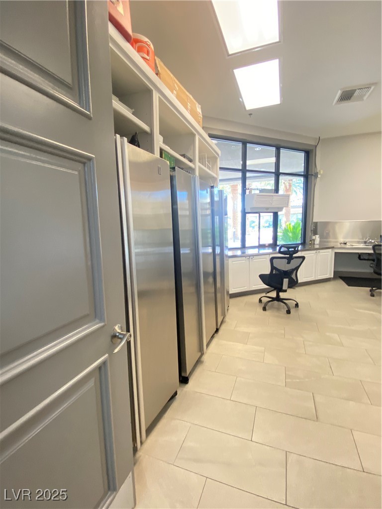118 Castle Course Avenue Las Vegas, NV 89148 - Photo 37 of 56 Kitchen featuring freestanding refrigerator, white cabinetry, built in study area, open shelves, and stainless steel refrigerator