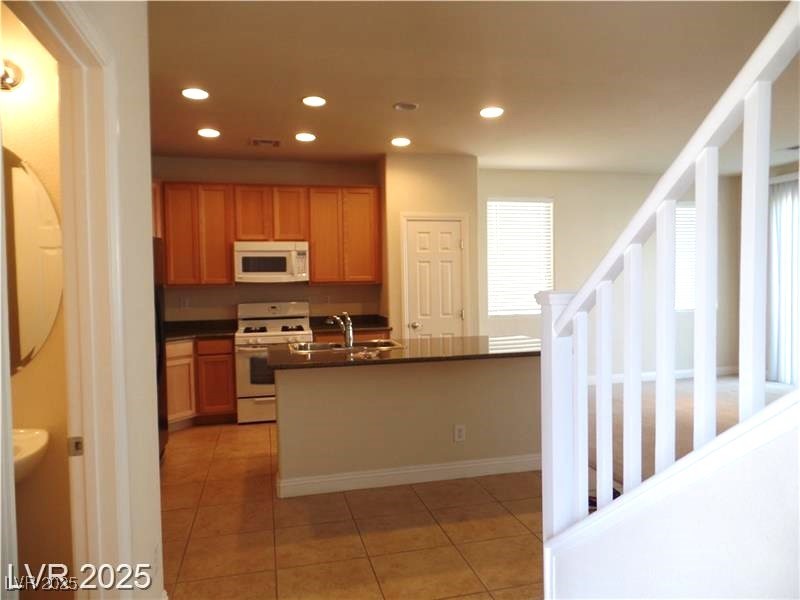 118 Castle Course Avenue Las Vegas, NV 89148 - Photo 6 of 56 Kitchen featuring dark countertops, white appliances, light tile patterned flooring, recessed lighting, and a kitchen island with sink