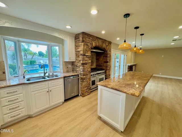 a kitchen with stainless steel appliances granite countertop a sink a stove and a refrigerator
