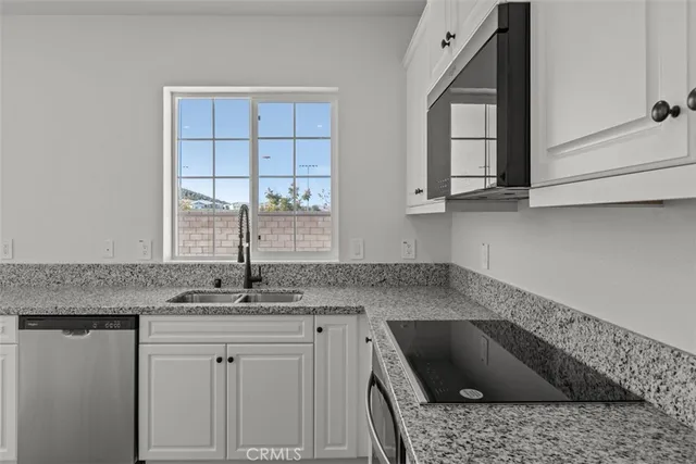 a kitchen with granite countertop a sink a stove and cabinets