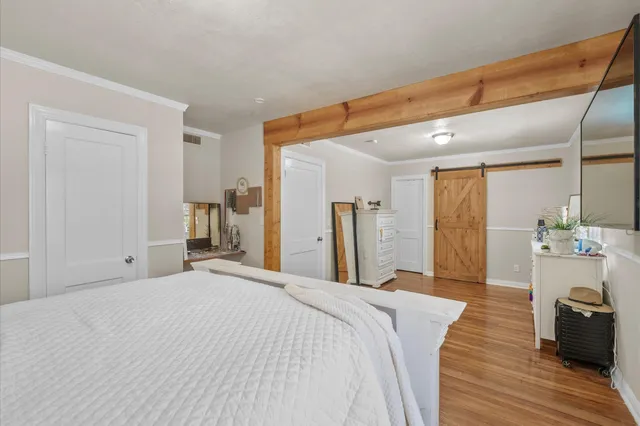 a bedroom with a large bed and wooden floor