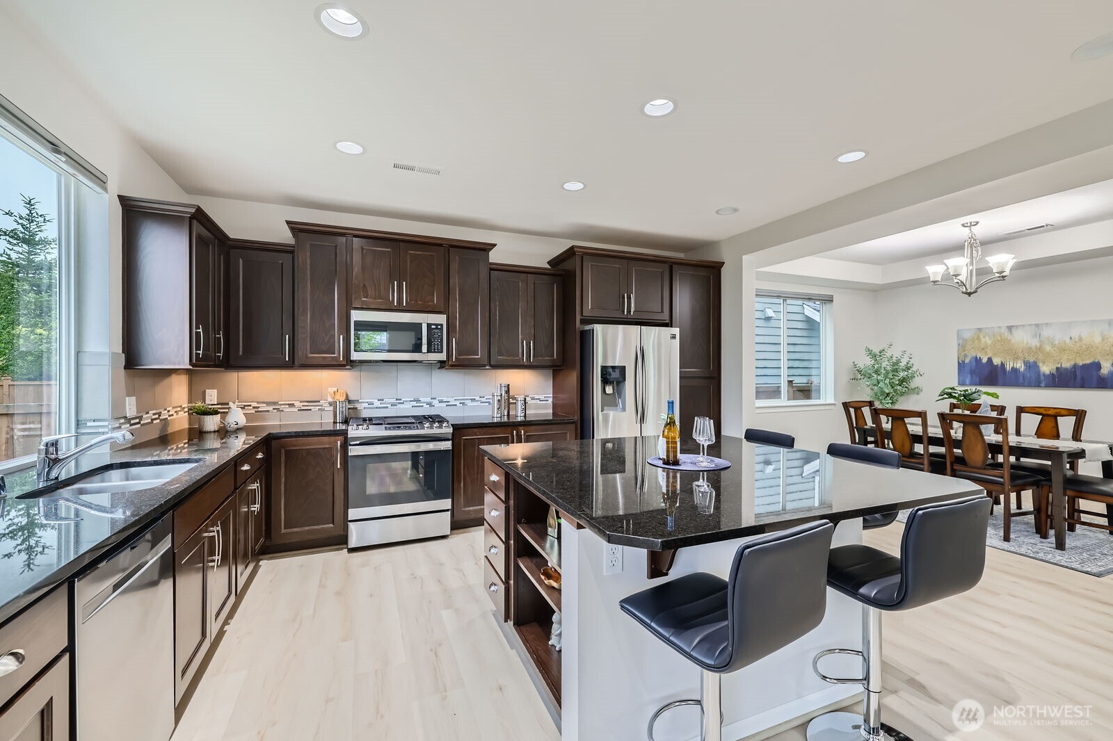 3720 195th Place Southeast Bothell, WA 98012 - Photo 9 of 32 a kitchen with stainless steel appliances granite countertop a stove top oven a sink dishwasher a dining table and chairs with wooden floor