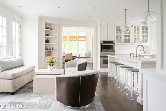 a living room with kitchen island furniture a flat screen tv and a large window