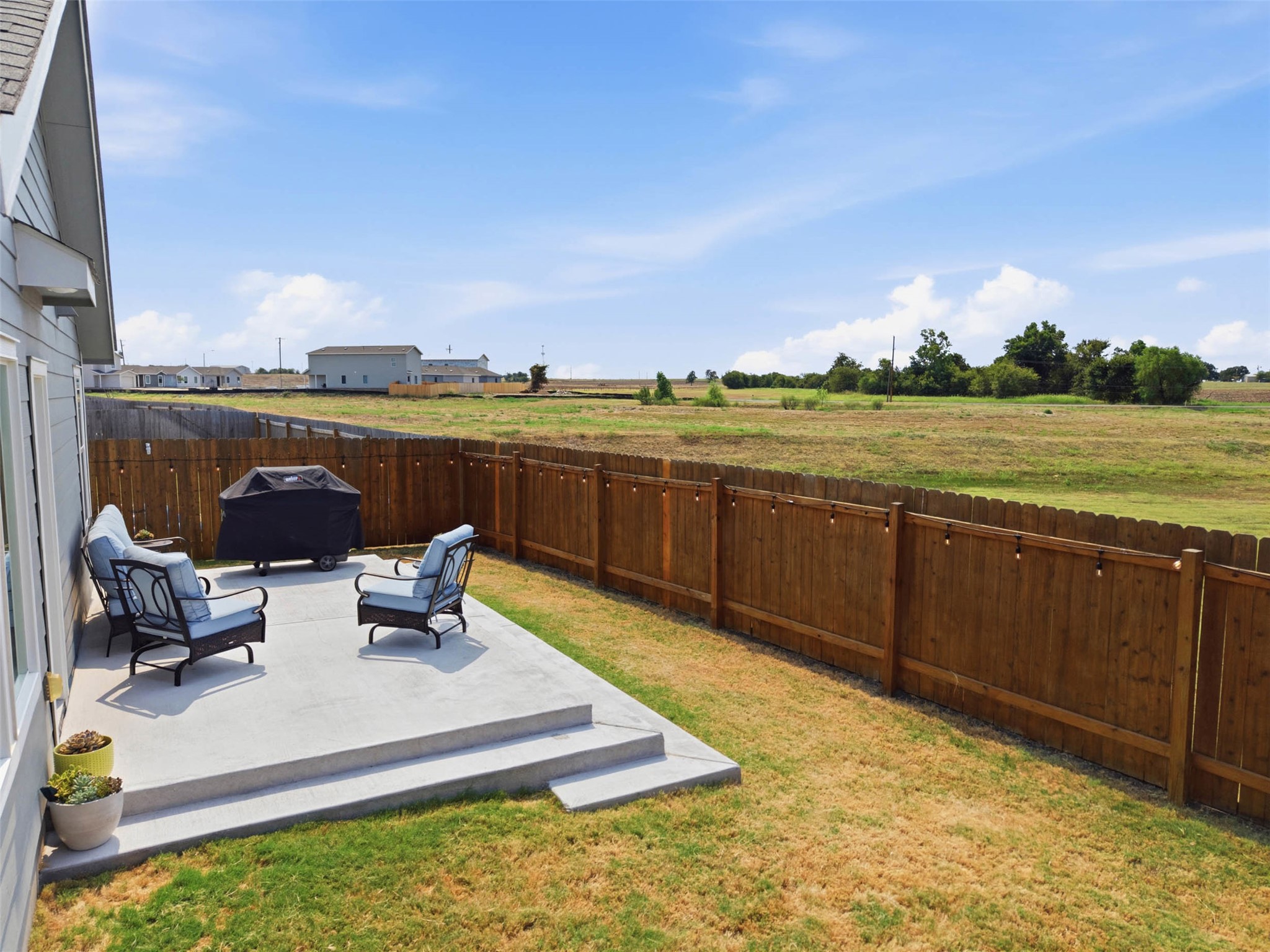 171 Cattle Queen Road Jarrell, TX 76537 - Photo 31 of 38 A concrete patio steps down to the grass yard bordered by a wooden privacy fence.
