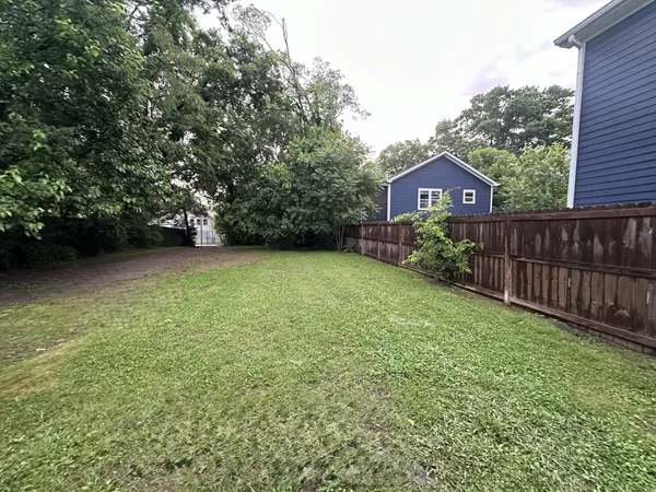 a view of a yard in front of a house with large trees