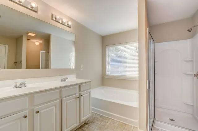 a bathroom with a bathtub a double vanity sink and mirror