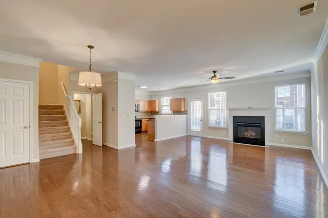 a view of a livingroom with wooden floor and a kitchen