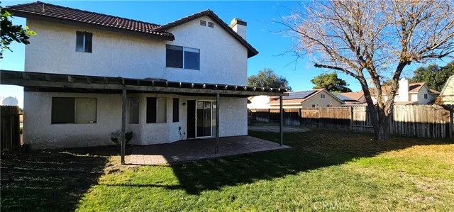 a view of a white house next to a yard with a large tree