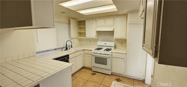 a kitchen with a sink a stove and white cabinets
