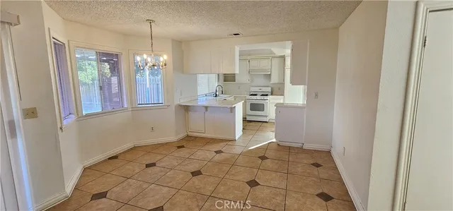 a large white kitchen with granite countertop a stove sink and dishwasher