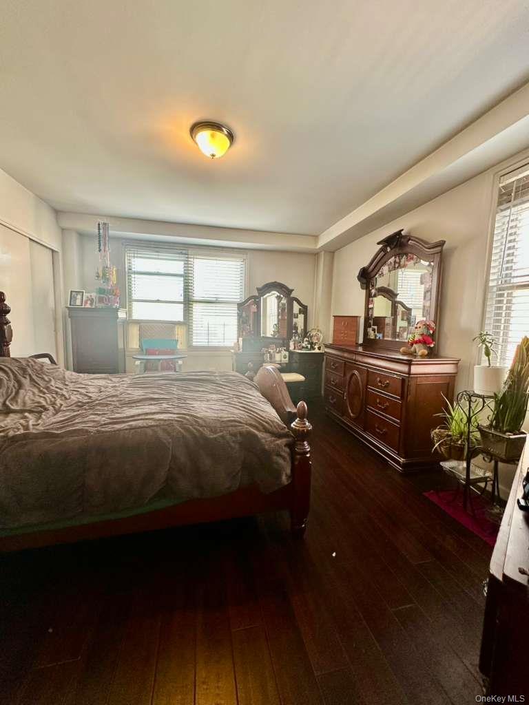 97-07 63rd Road, Unit 6H Queens, NY 11374 - Photo 15 of 17 a bed sitting in a bedroom next to a window with potted plants on dresser