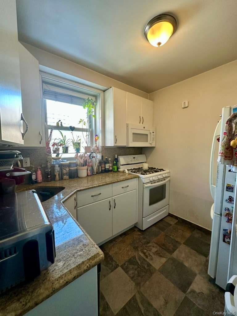 97-07 63rd Road, Unit 6H Queens, NY 11374 - Photo 5 of 17 a kitchen with stainless steel appliances granite countertop a stove a sink and a refrigerator