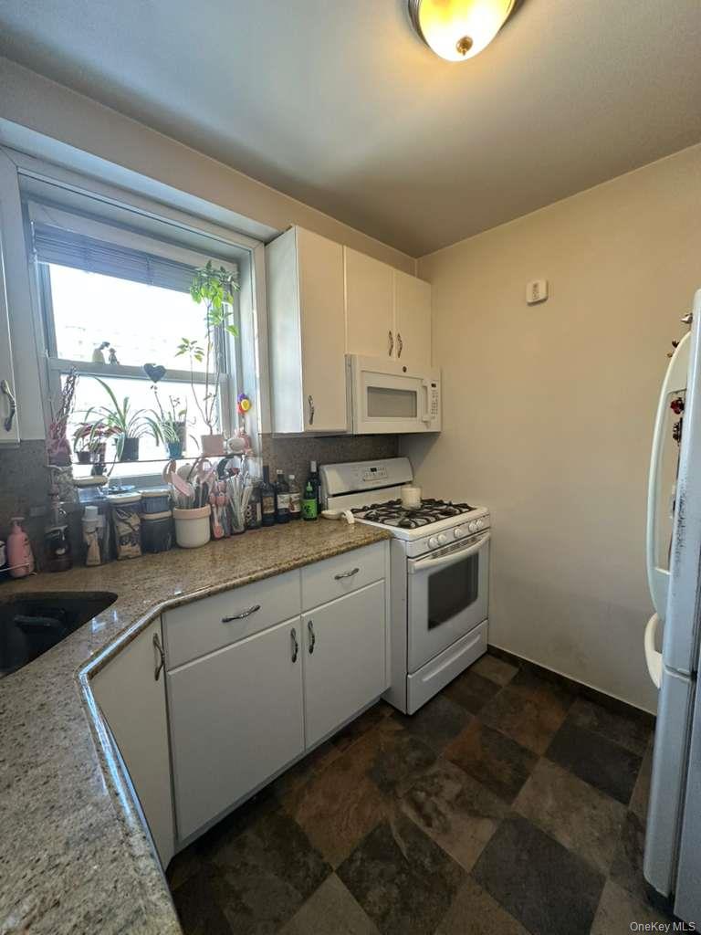 97-07 63rd Road, Unit 6H Queens, NY 11374 - Photo 7 of 17 a kitchen with stainless steel appliances granite countertop a stove a sink and a microwave