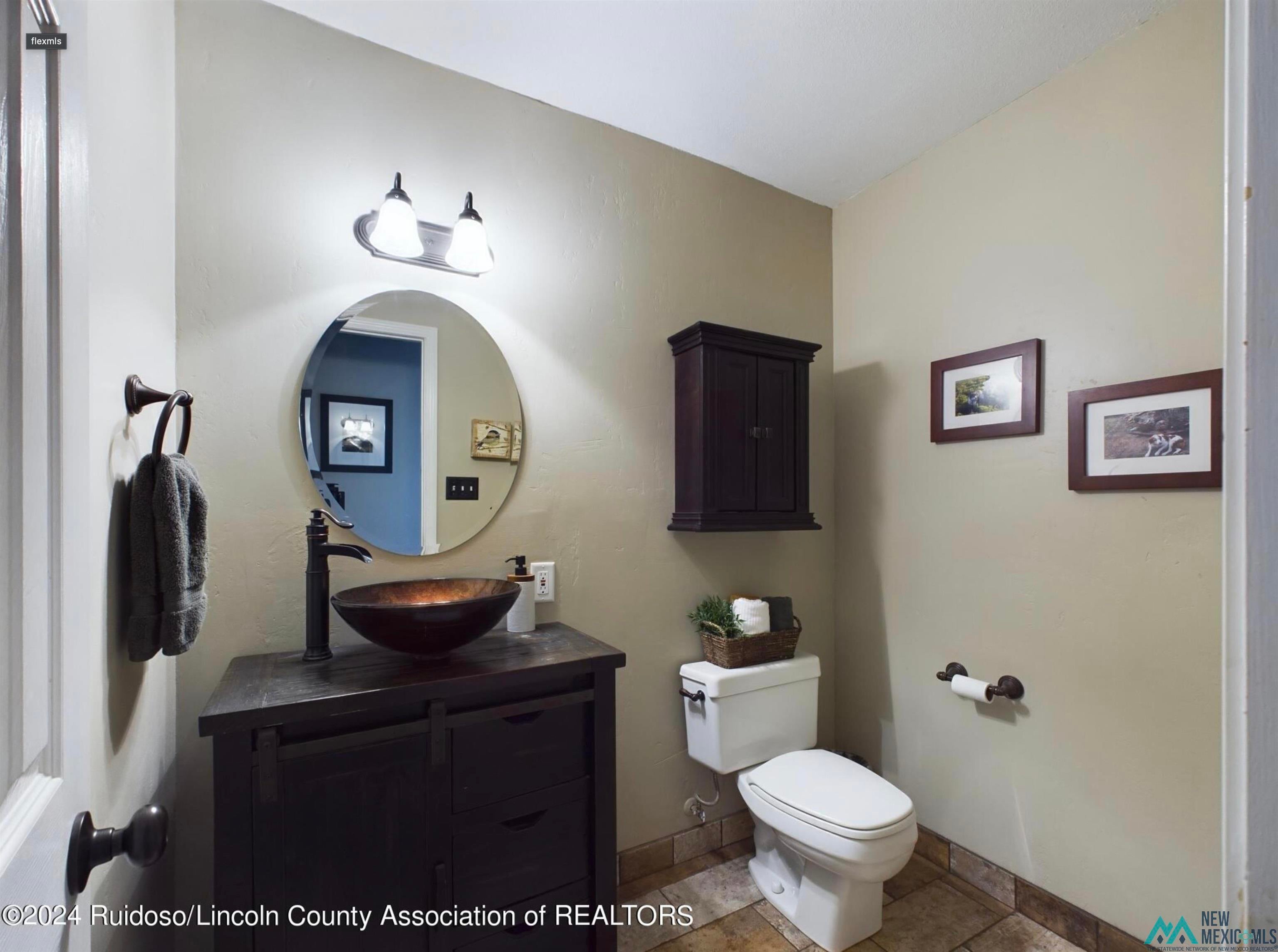333 Ll Davis Drive Ruidoso, NM 88345 - Photo 16 of 25 Bathroom featuring a dark wood-finish vanity with a vessel sink, an oval wall mirror, and a two-light vanity fixture