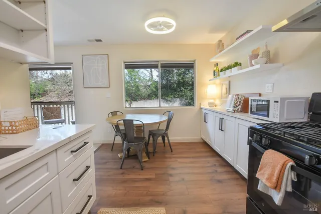 a kitchen with stainless steel appliances a stove a sink a dining table and chairs