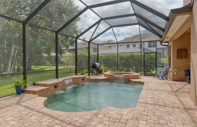 a view of a white house with a small yard plants and a large tree