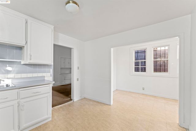 a kitchen with white cabinets and window