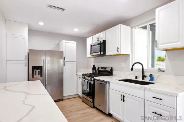a kitchen with stainless steel appliances granite countertop a refrigerator sink and white cabinets