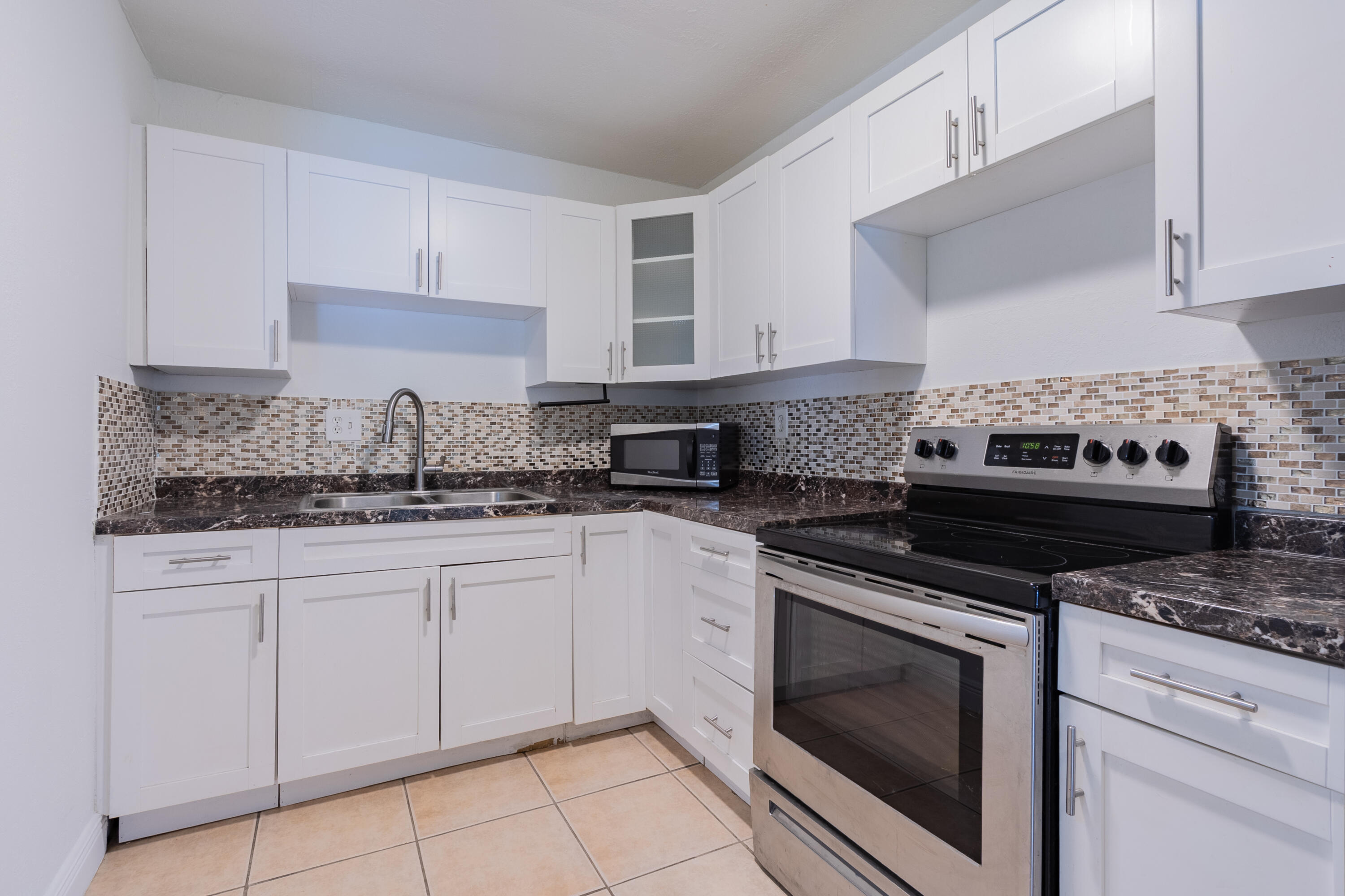 a kitchen with granite countertop white cabinets and appliances